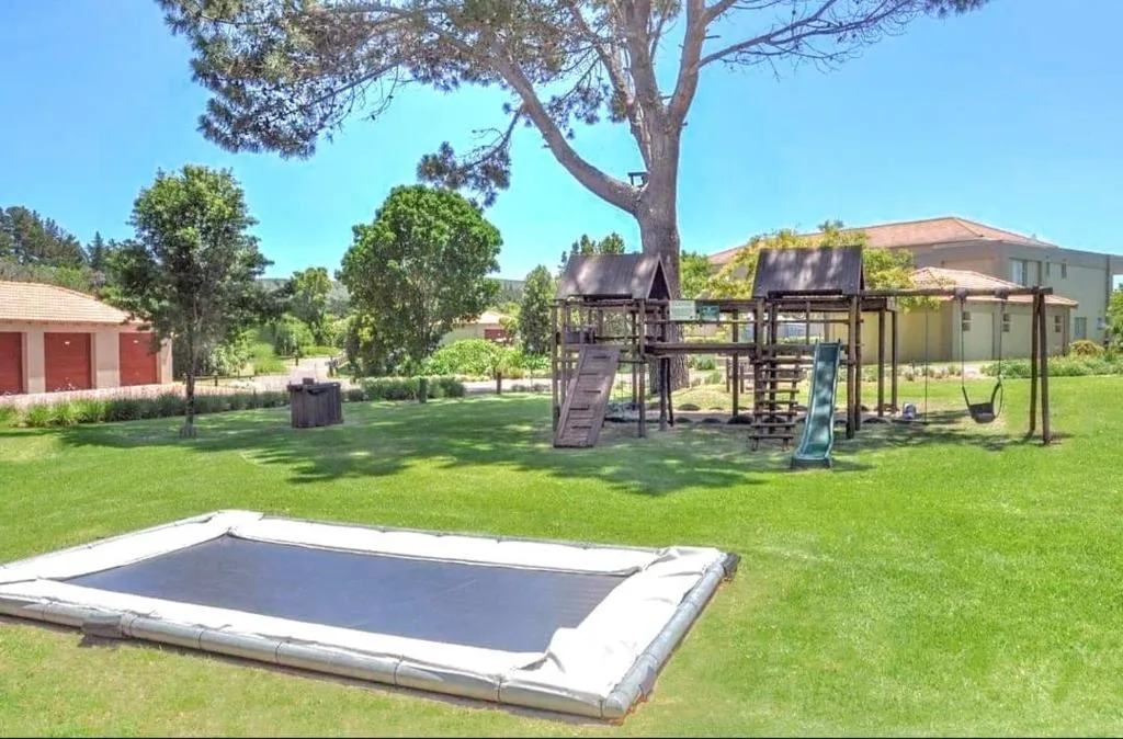 Spacious garden with trampoline, playground, and main house visible