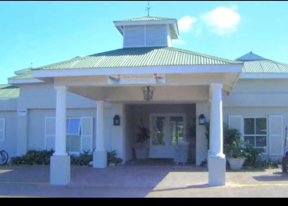 White building with covered entrance portico and metal roof in daylight