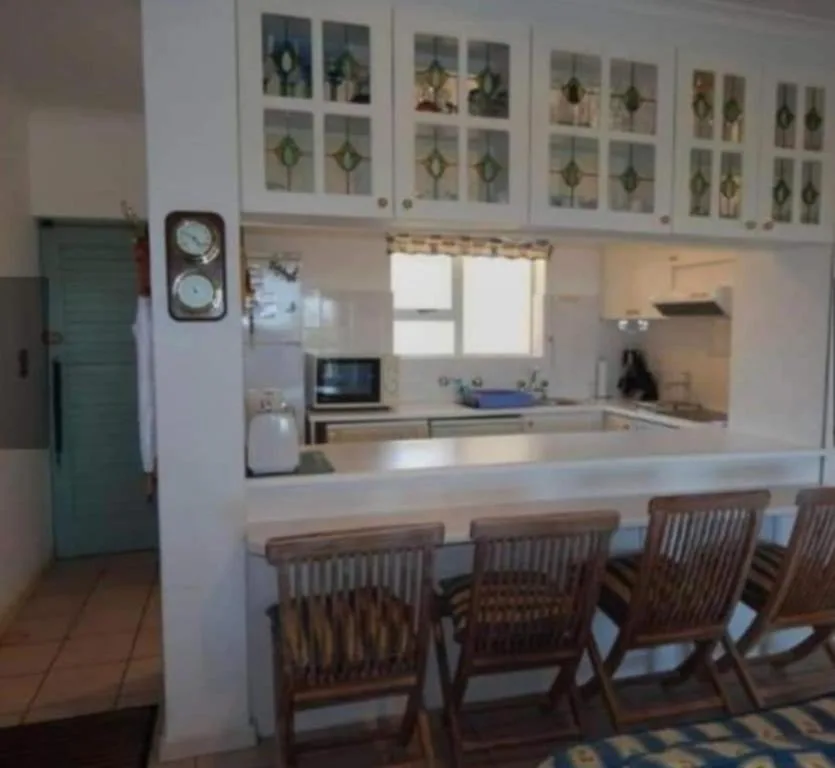 Open-plan kitchen with white cabinetry, counter seating, and modern appliances