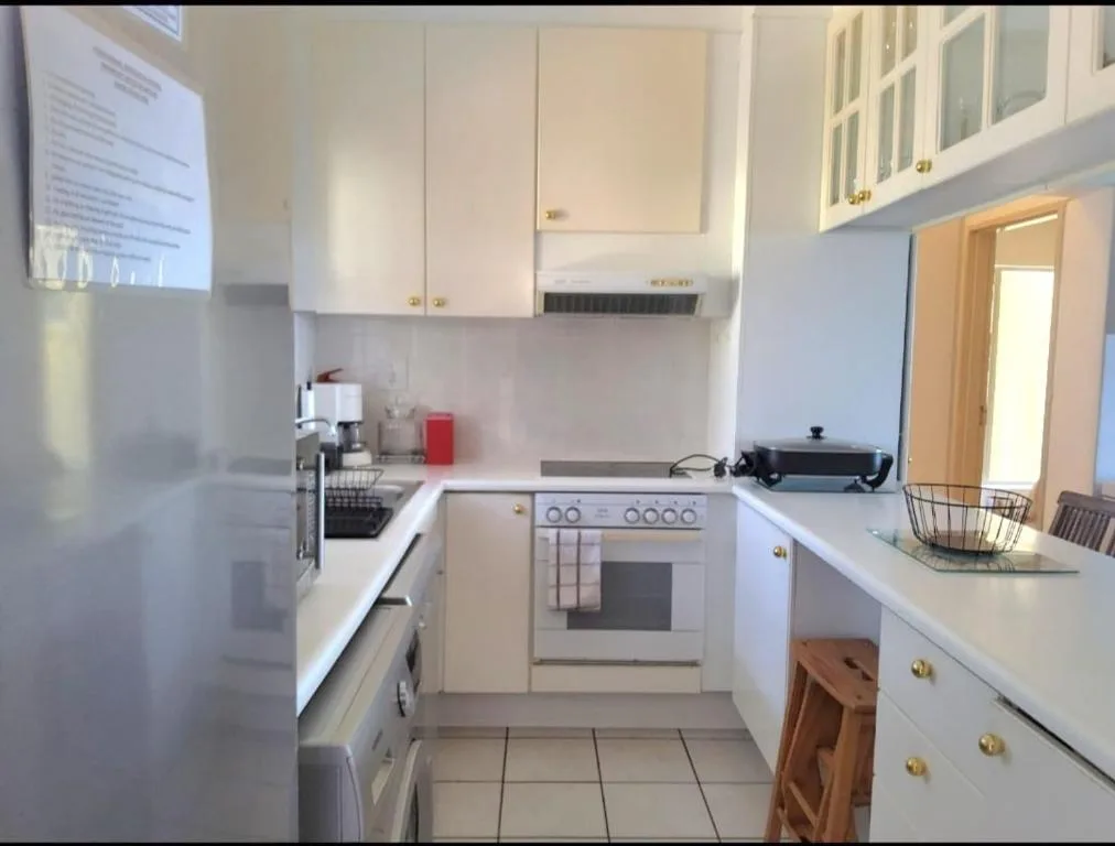 Bright compact kitchen with white cabinetry, stove, and countertops