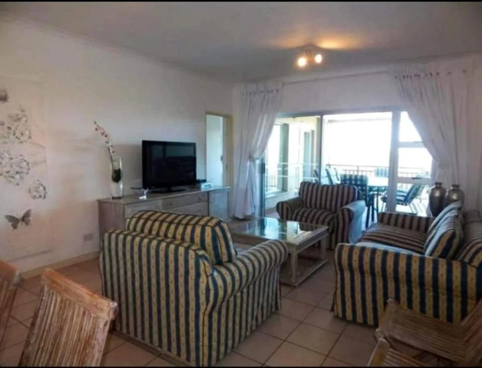 Striped armchairs and TV in bright living room with ocean view doors