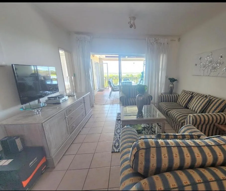 Spacious living room with striped sofa, TV, and deck views beyond