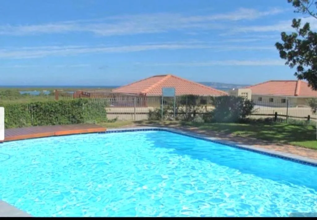 Sparkling blue swimming pool with house and ocean view beyond