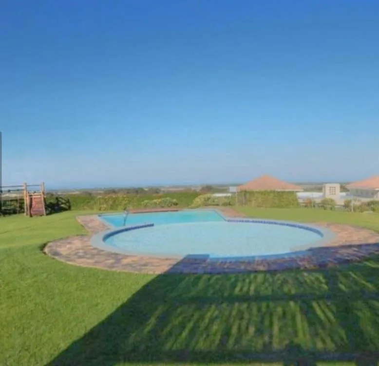 Curved swimming pool in manicured garden with mountain views beyond