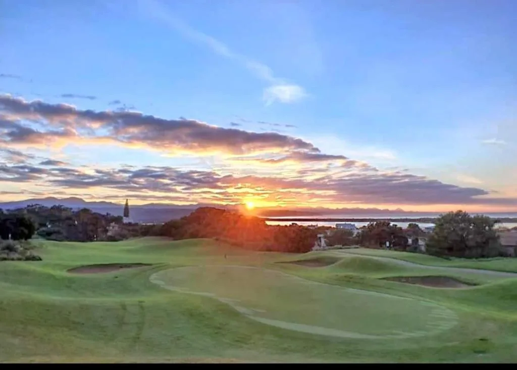 Stunning sunset over golf course with lagoon and mountains beyond