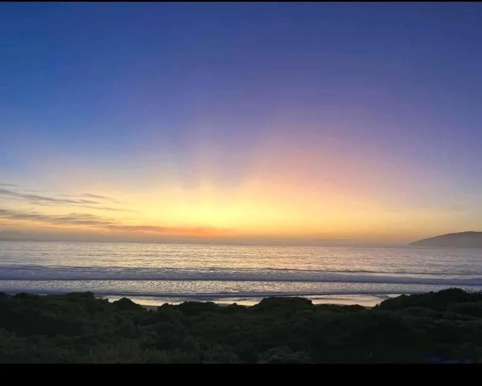 Sunset over the ocean with golden sky reflecting on calm waters