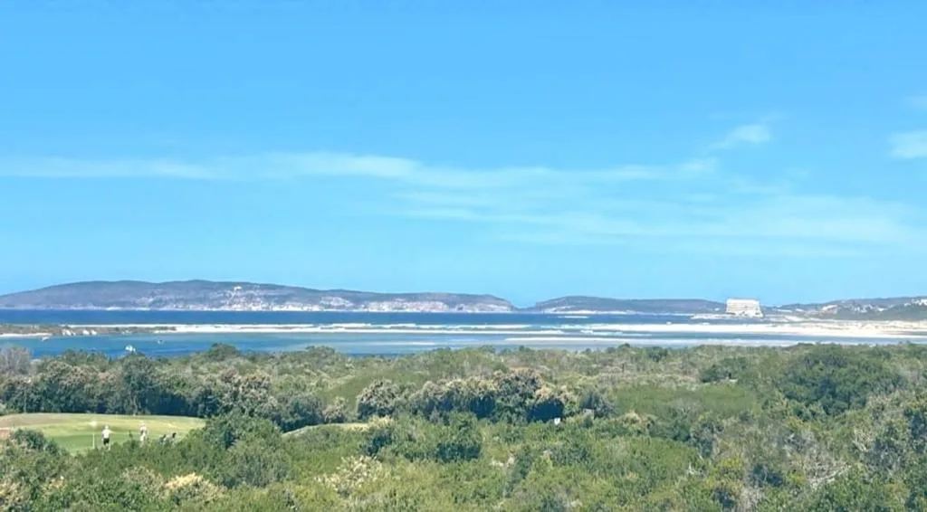 Panoramic coastal view of lagoon, mountains, and forested landscape below