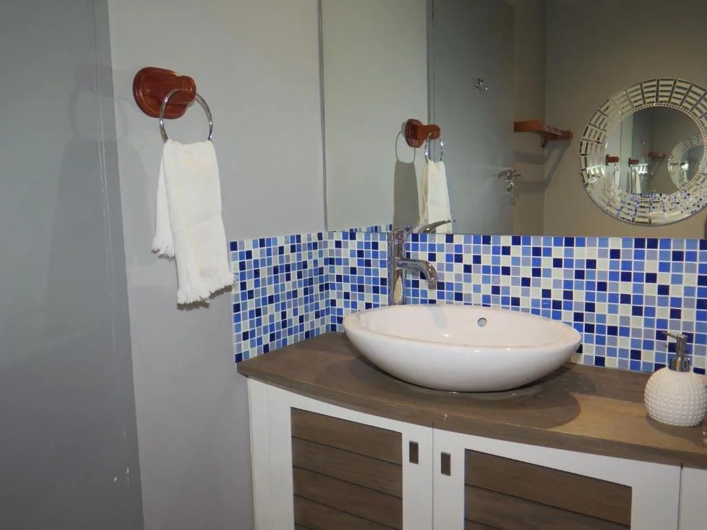 Modern bathroom with blue mosaic tile backsplash and round white vessel sink