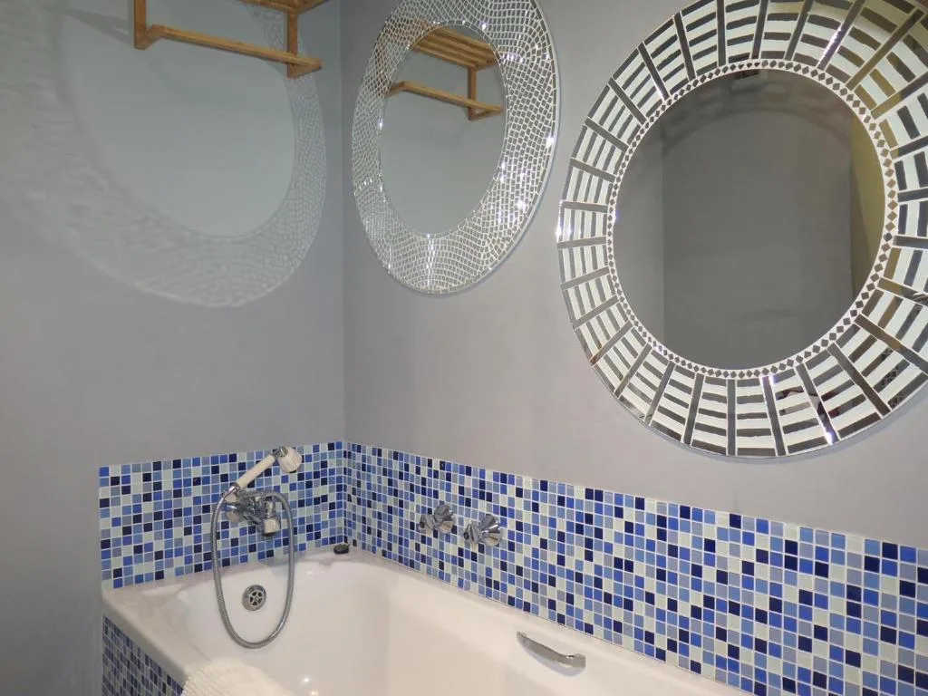 Modern bathroom with blue mosaic tile backsplash and decorative round mirrors
