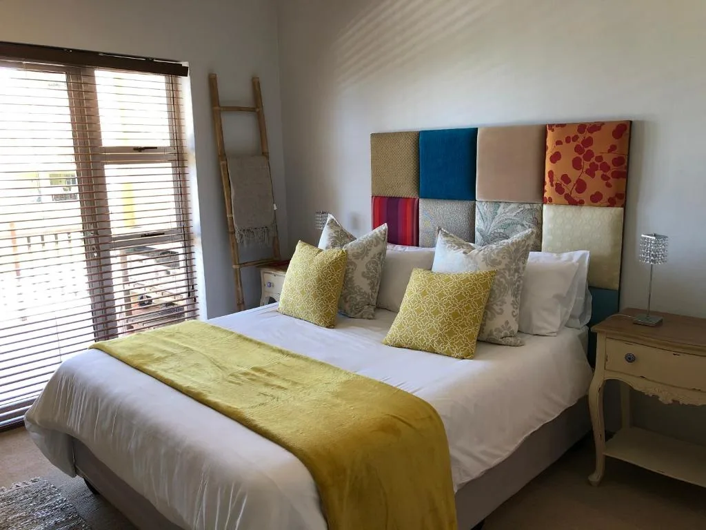 Bright bedroom with queen bed, colorful patchwork headboard, yellow accents