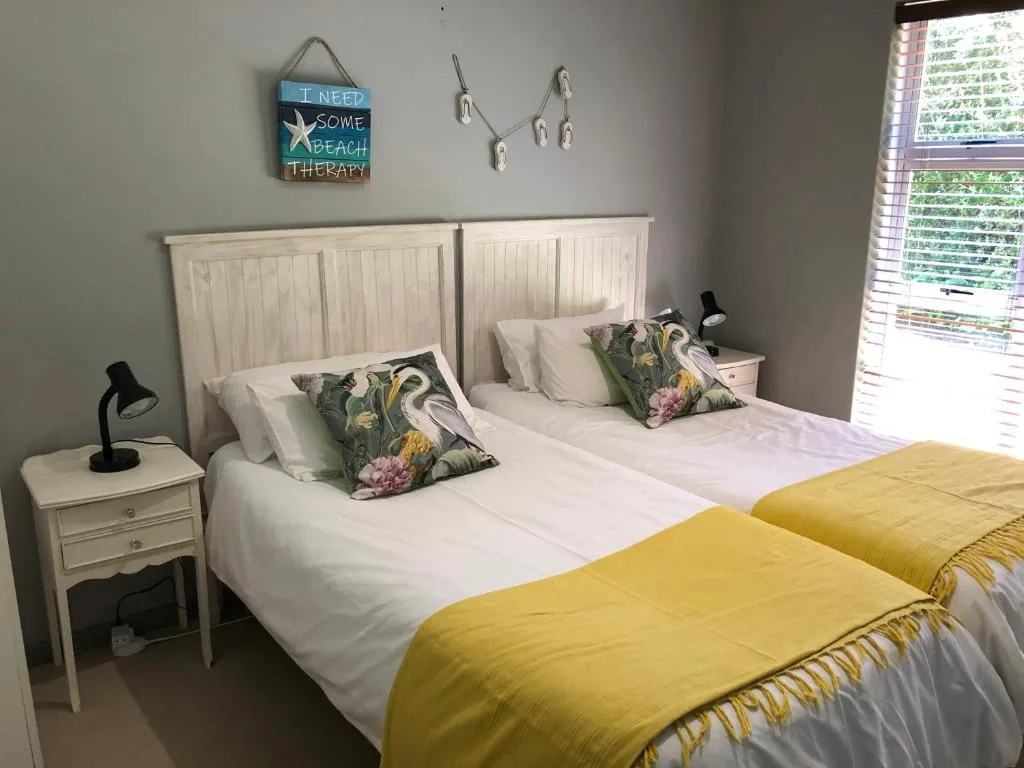 Twin beds with white headboards, yellow throws, and patterned cushions