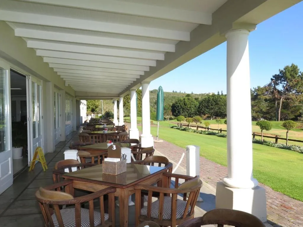 Covered patio with dining tables overlooking manicured gardens and green fields
