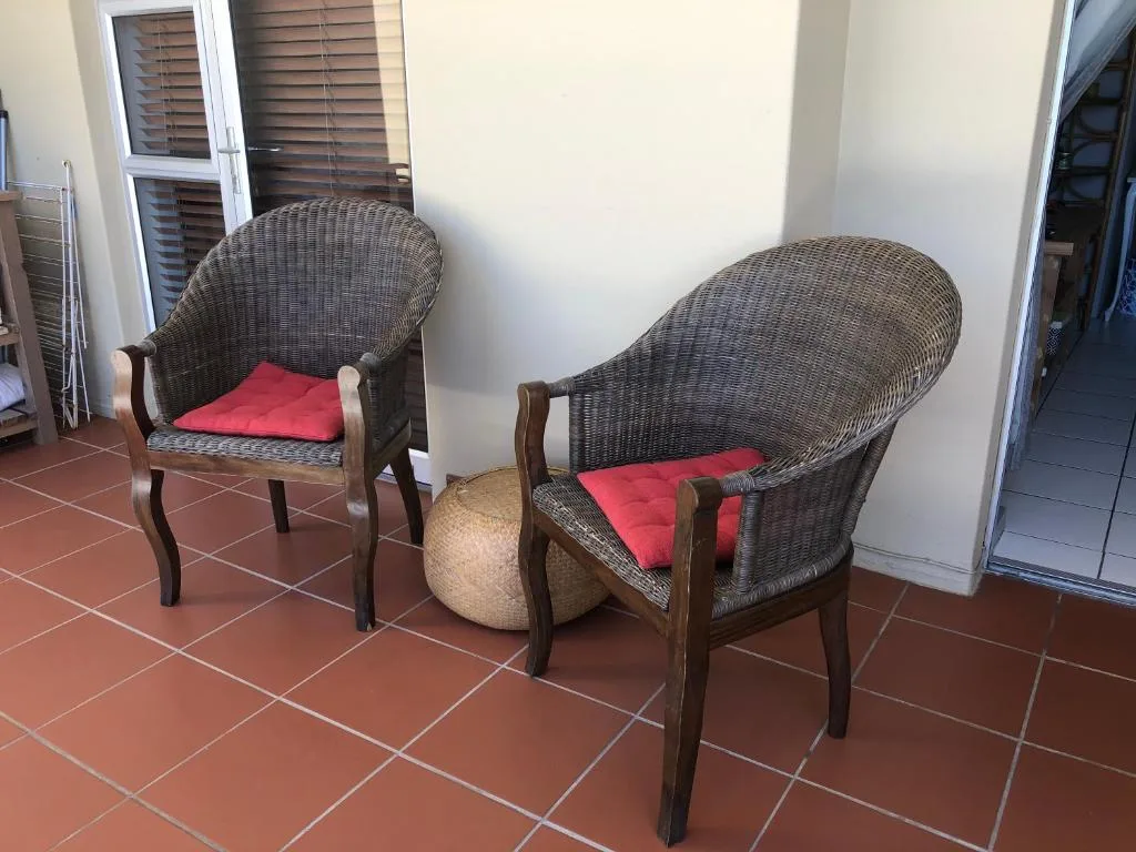 Two wicker armchairs with red cushions on covered patio area