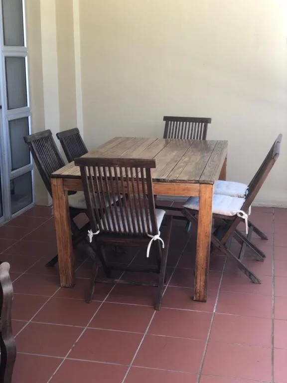 Wooden dining table with black chairs on tiled patio area