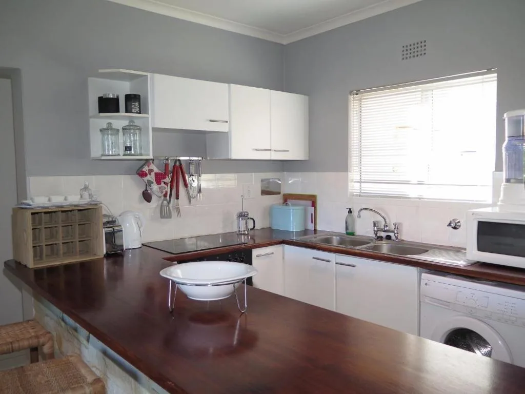 Modern kitchen with white cabinetry, dark wood countertops, and stainless steel appliances