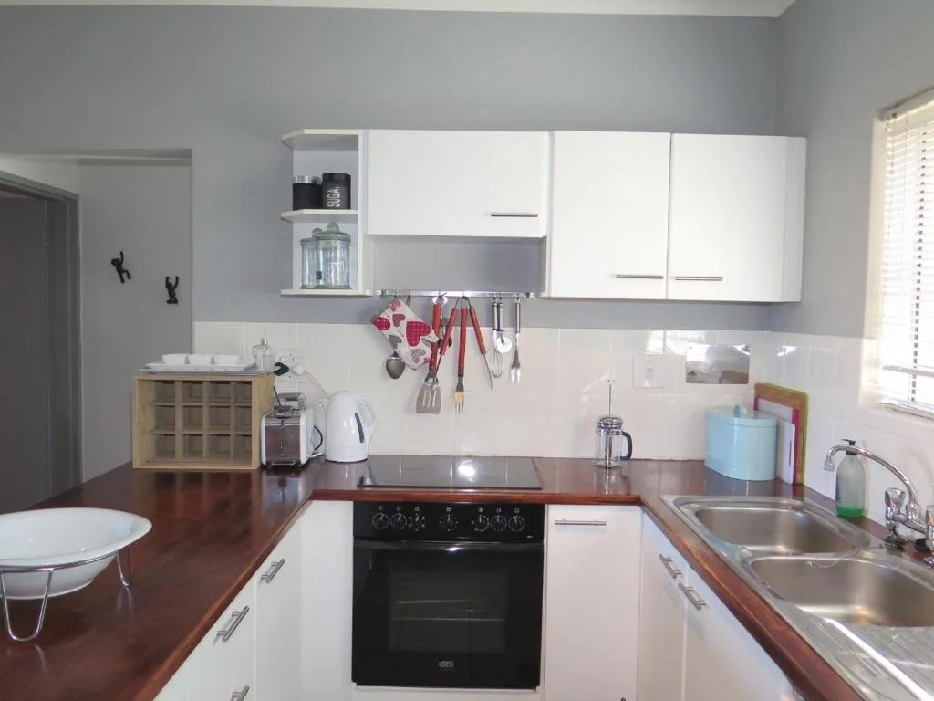 Modern kitchen with white cabinetry, dark oven, and wooden countertops