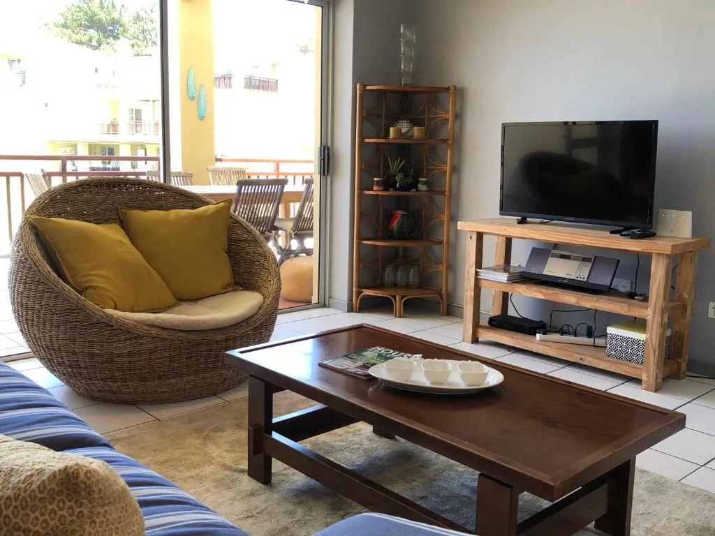 Spacious lounge with wicker chair, TV, and deck access