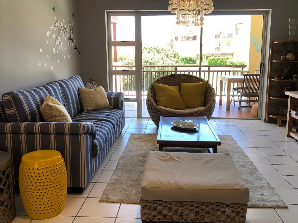 Bright lounge with striped sofa, woven chair, and ocean views through large glass doors