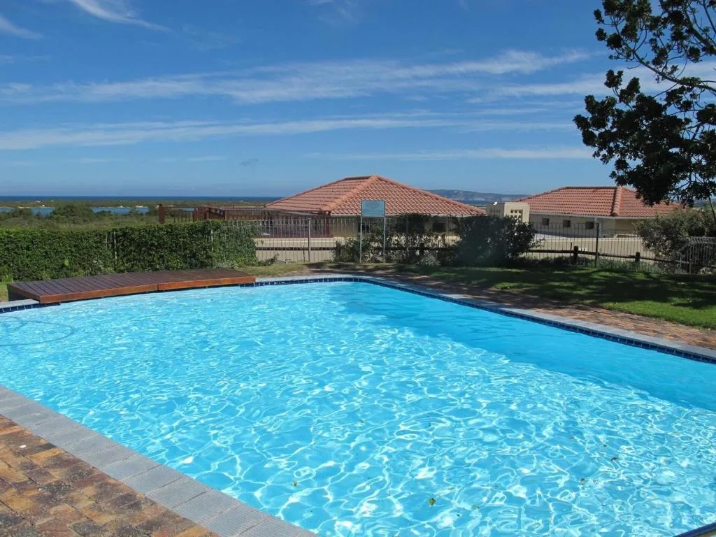Crystal-clear swimming pool with coastal views and terracotta-roofed buildings