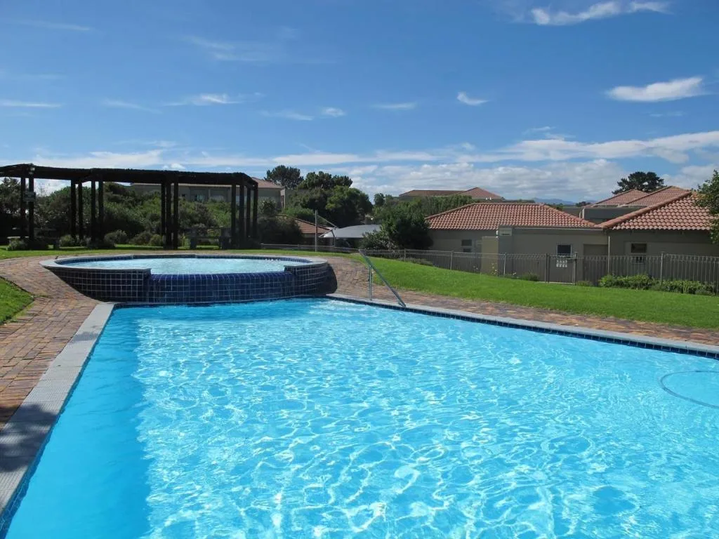 Rectangular swimming pool with circular spa pool beside pergola and gardens