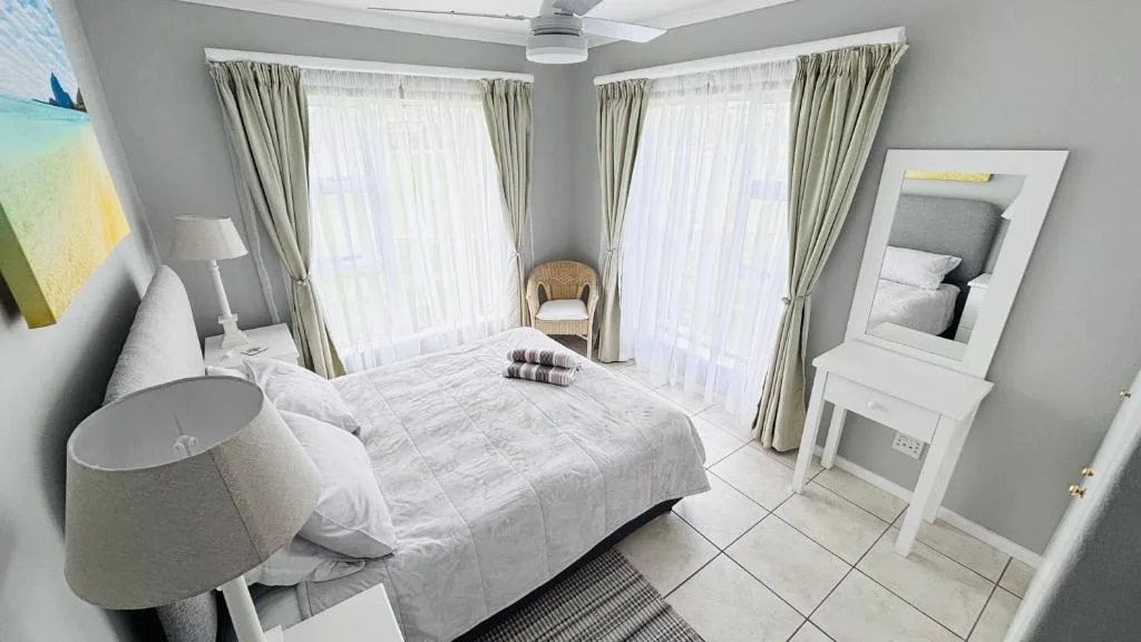 Bright bedroom with white linens, large windows, and modern decor