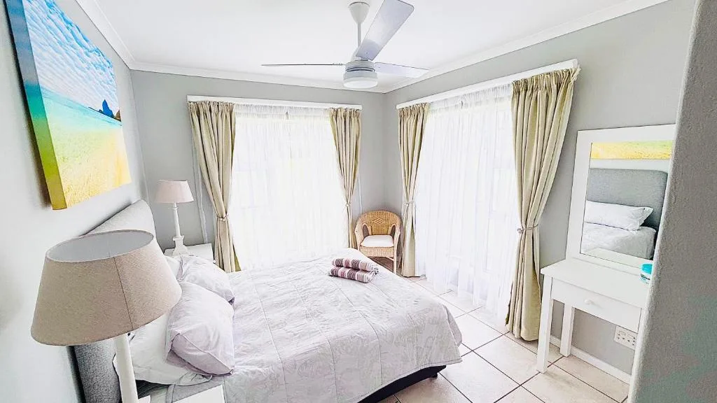 Bright bedroom with queen bed, cream curtains, and glass doors to outdoor area