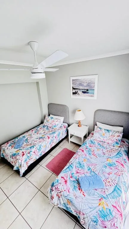 Twin bedroom with colorful bedding and ceiling fan in bright apartment