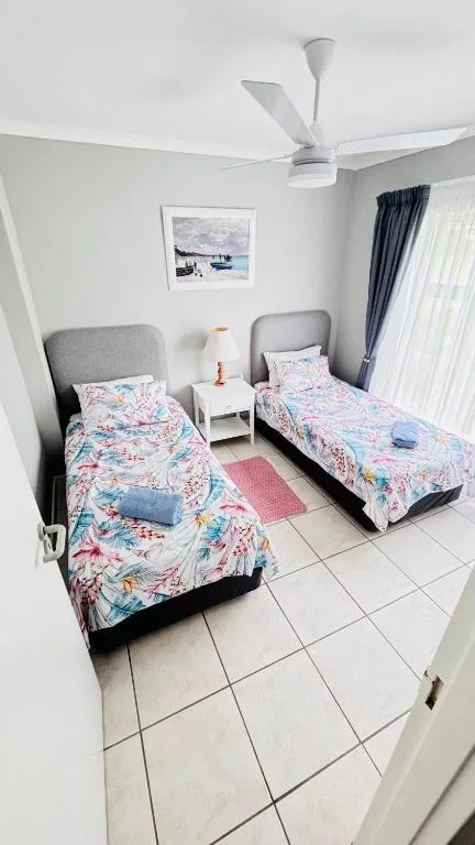 Twin bedroom with colorful floral bedding, grey headboards, and ceiling fan