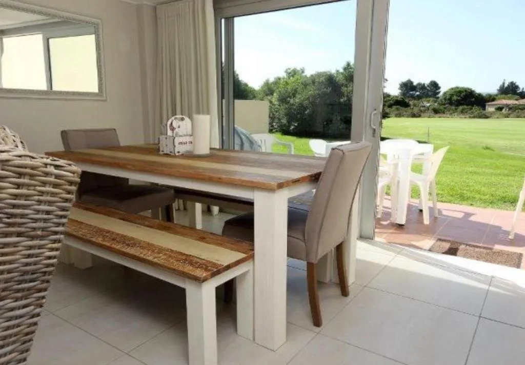 Wooden dining table with bench seating overlooking expansive garden lawn