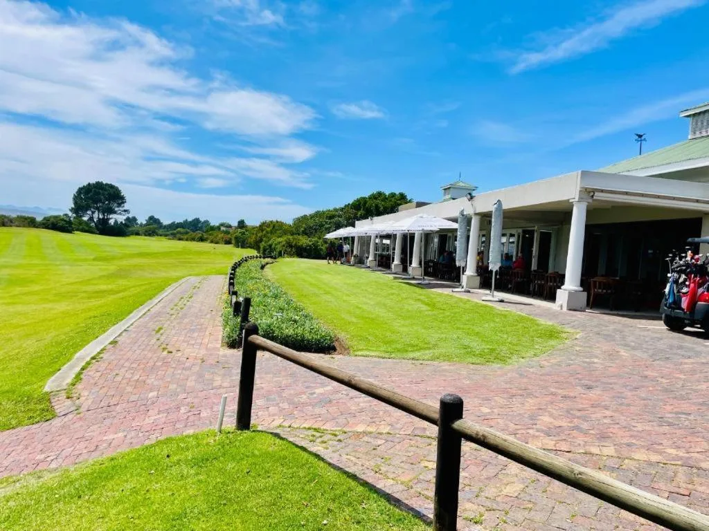 Modern property exterior with manicured lawns and columned veranda overlooking rolling greenery