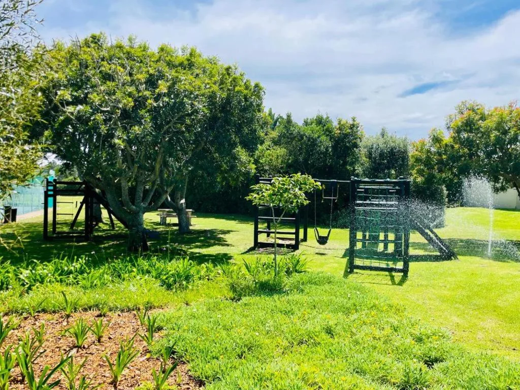 Large manicured garden with playground equipment and mature trees
