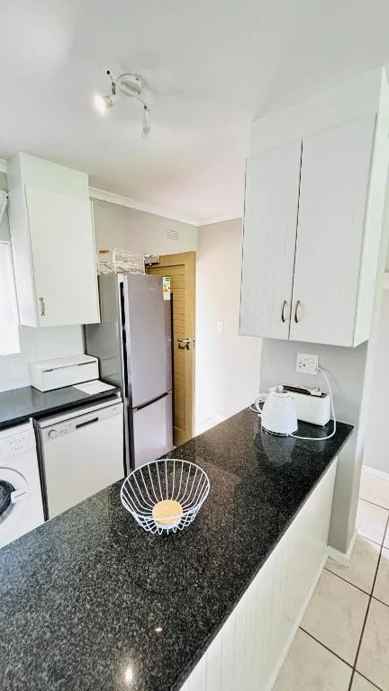 Modern kitchen with white cabinetry, dark countertop, and stainless steel appliances