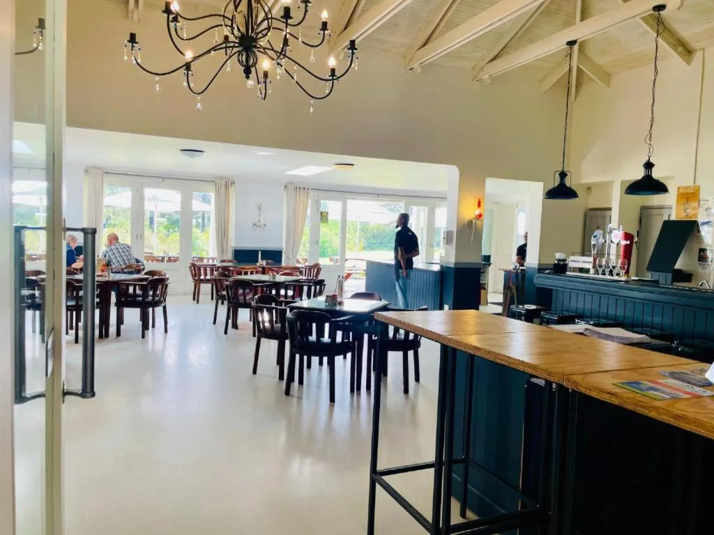 Open-plan living area with dining tables, bar counter, and elegant chandeliers