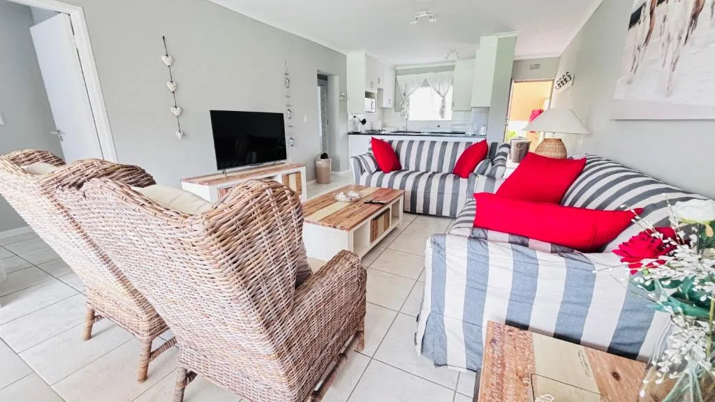 Open-plan lounge with striped sofa, wicker chairs, and flat-screen TV