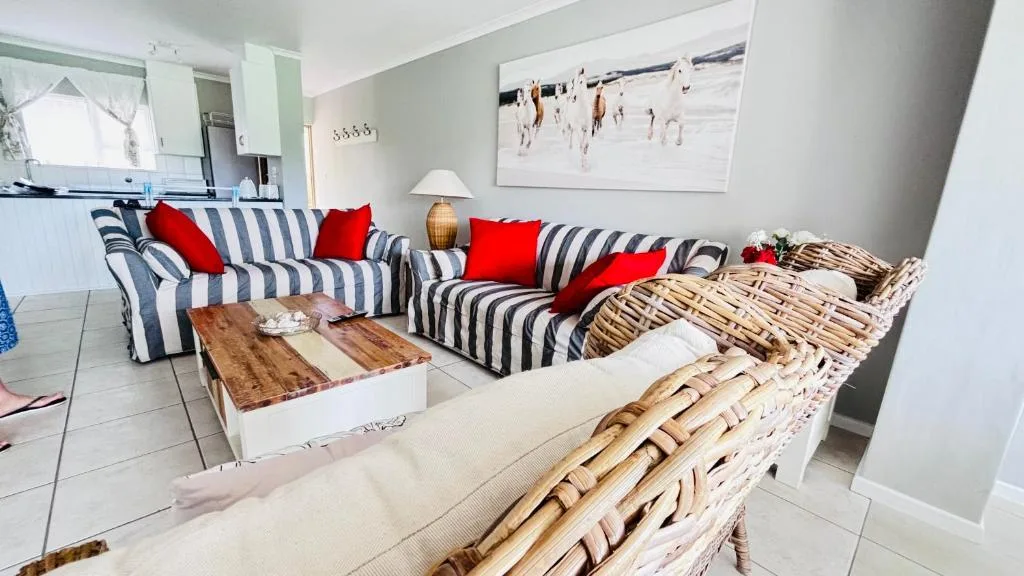 Bright living room with striped sofa, red cushions, and wicker furniture