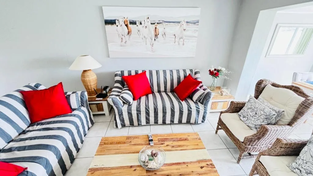 Bright lounge with striped sofas, red cushions, and wicker chairs