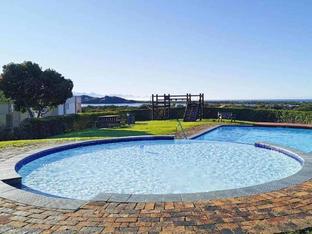 Two swimming pools with mountain and lagoon views beyond manicured gardens