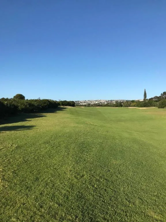 Expansive lawn with trees and town visible in distant background
