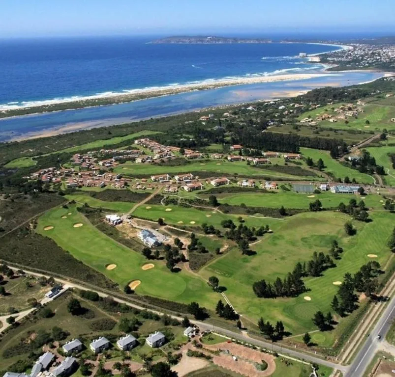 Aerial view of coastal property with lagoon, beach, and golf course