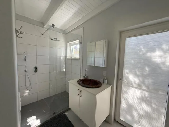 Modern bathroom with walk-in shower, white vanity, and round sink basin