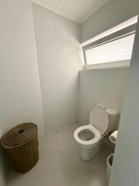 Modern bathroom with toilet, window, and woven laundry basket