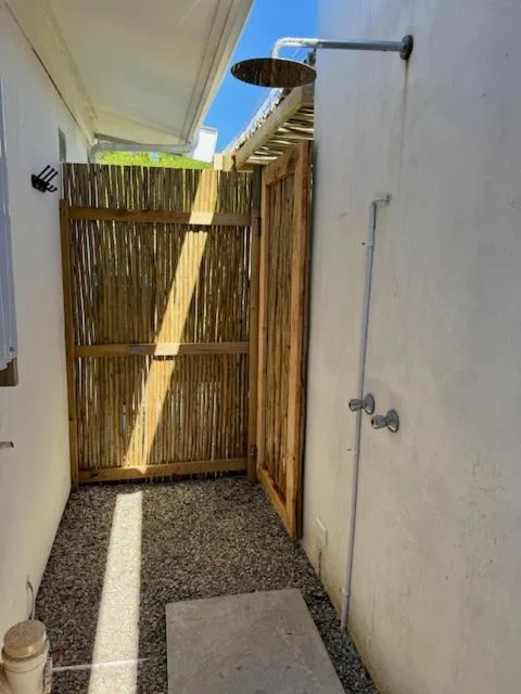 Outdoor shower enclosure with wooden slats and rainfall showerhead