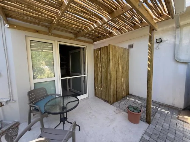 Covered outdoor patio with wooden pergola, seating, and potted plants