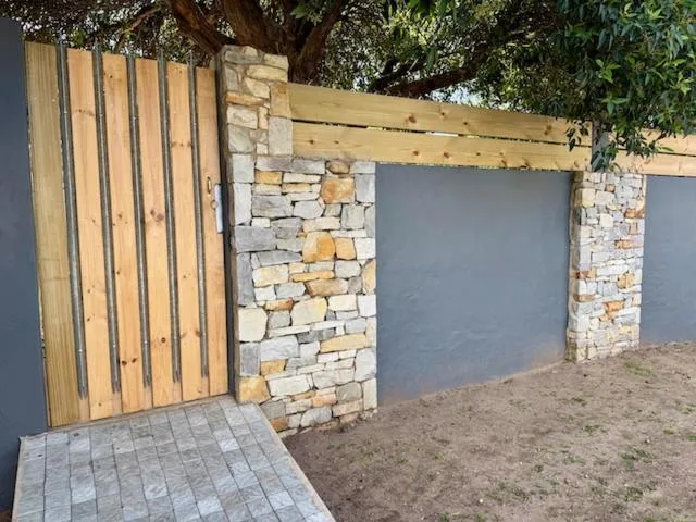 Modern wooden and stone entrance gate with paved pathway to property