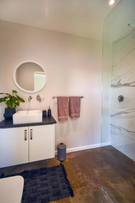 Modern bathroom with circular mirror, vessel sink, and walk-in shower