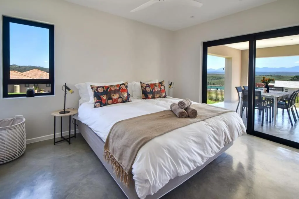 Bright bedroom with queen bed, mountain views through large windows and doors