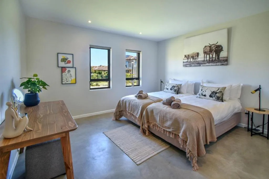 Bright bedroom with twin beds, large windows, and nature artwork