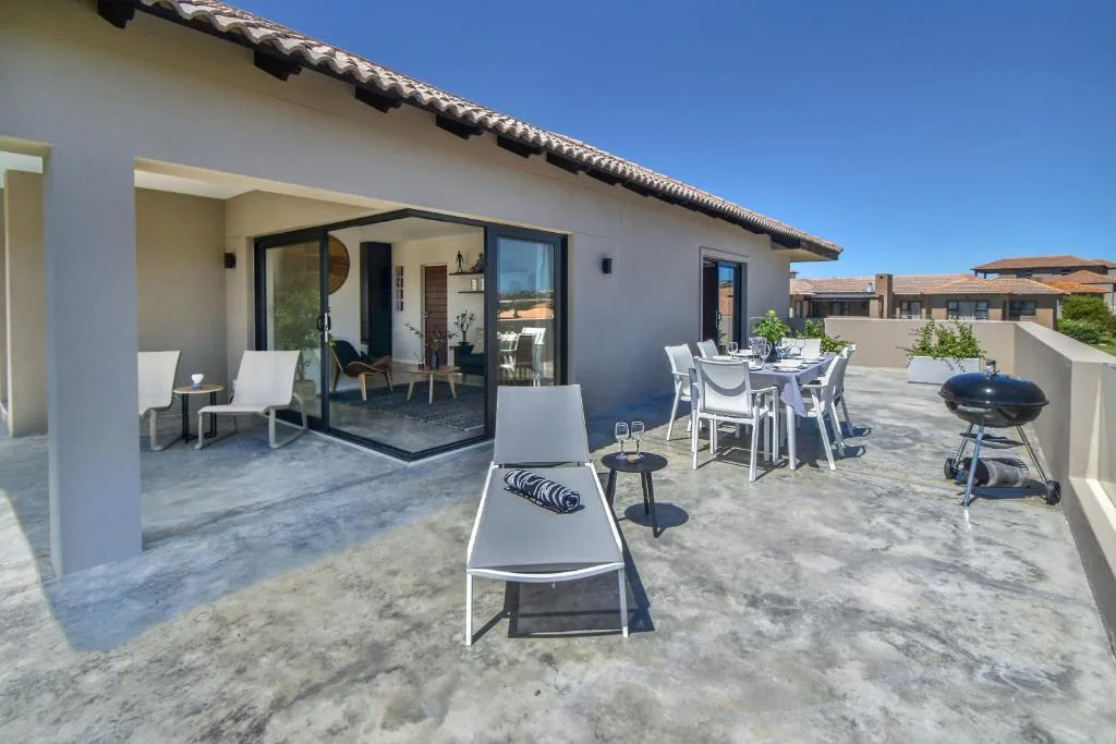 Spacious rooftop deck with loungers, dining table, and braai grill