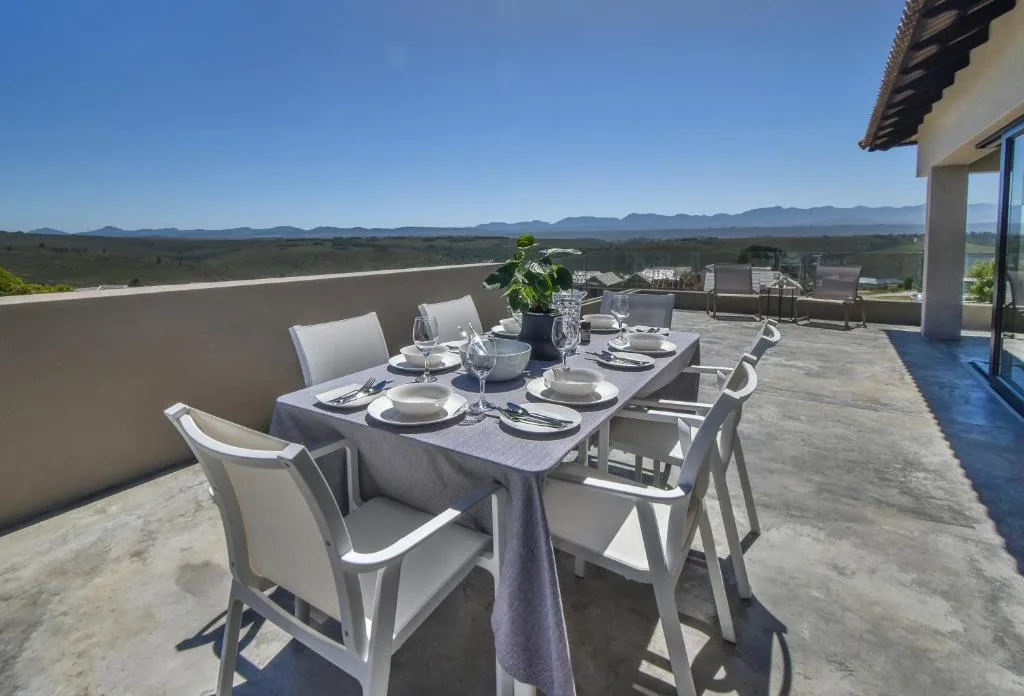 Outdoor dining table set for six on rooftop terrace with mountain views