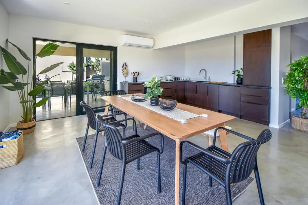 Modern dining table with black chairs overlooking kitchen and deck area